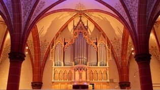 Eine Orgel mit bunter Hintergrundbeleuchtung mit einem Kirchengewölbe